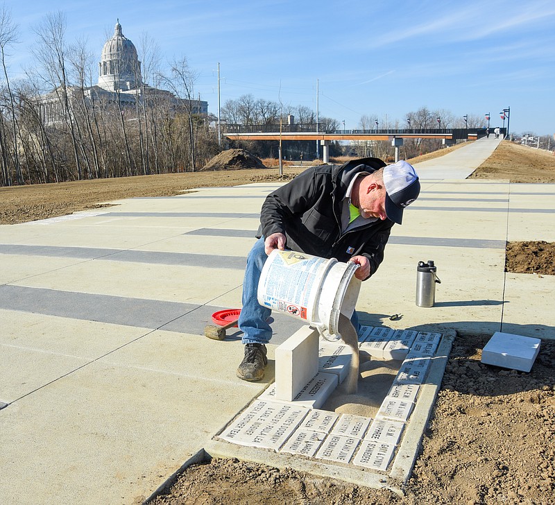 Andrew Bax of Jefferson City Parks, Recreation and Forestry Department places blank pavers in the opening after two inscribed ones were removed by officials Thursday morning. The pavers, which were located just beyond the Bicentennial Bridge, were inscribed with the words "Union Camp Lillie notes: Deciding against attack the Confederate Army under Gen. Sterling Price turned from Jefferson City Oct. 7, 1864". Funds raised through sales of the pavers go toward the bridge. (Julie Smith/News Tribune)