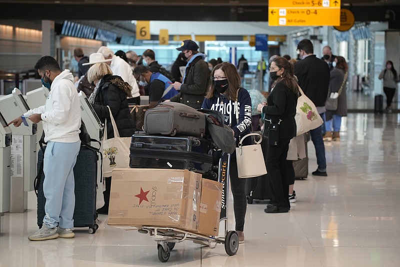Travelers queue up at the United American Airlines check-in kiosks in the terminal of Denver International Airport Sunday, Dec. 26, 2021, in Denver. Airlines canceled hundreds of flights Sunday, citing staffing problems tied to COVID-19 to extend the nation's travel problems beyond Christmas. (AP Photo/David Zalubowski)