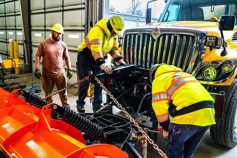 Roger Saleny, Grant Kleindienst, Mike Blankenship and Tyler Ford attach a plow to the front of a MoDOT truck on Wednesday in Jefferson City. The forecast for Saturday calls for possible snow or freezing rain.