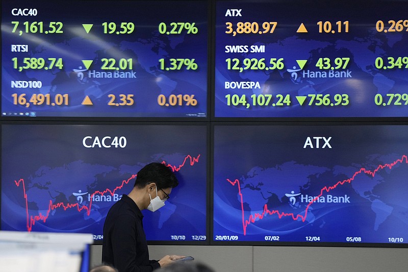 A currency trader walks past screens Thursday at a foreign exchange dealing room in Seoul, South Korea. Asian markets had a mixed day.
(AP/Lee Jin-man)