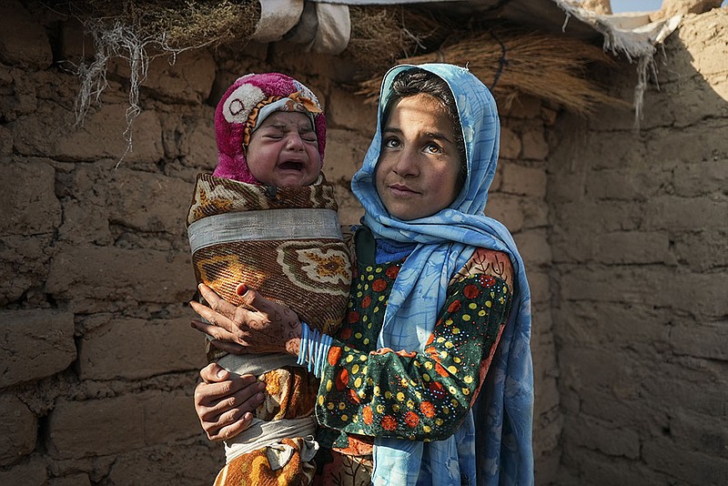 Qandi Gul holds her brother on Dec. 16 outside housing for those displaced by war and drought near Herat, Afghanistan. Gul’s father sold her into marriage without telling his wife, taking a down-payment so the rest of the family wouldn’t starve.
(AP/Mstyslav Chernov)