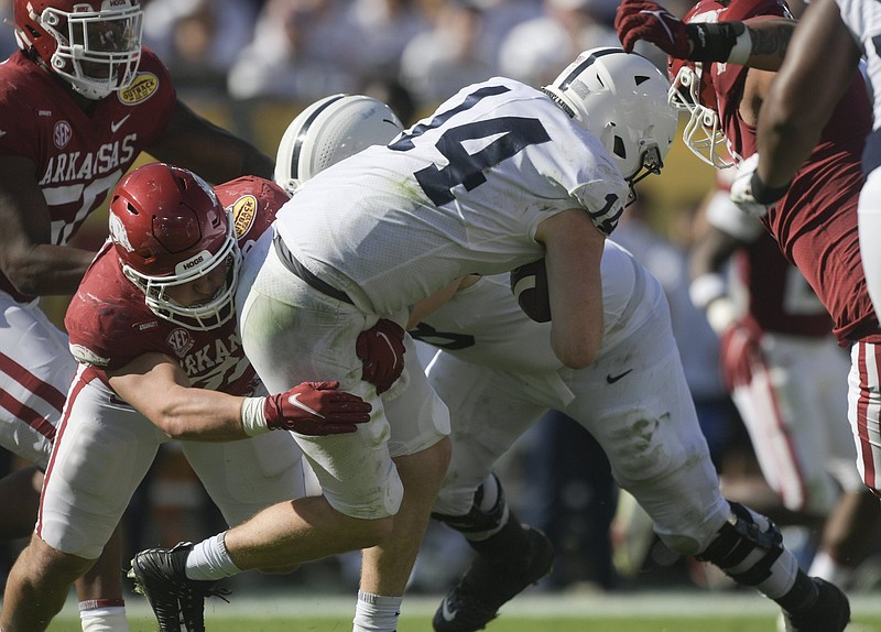 Arkansas senior linebacker Grant Morgan (left) tackles Penn State quarterback Sean Clifford during Saturday’s Outback Bowl in Tampa, Fla. For much of the game, Morgan was on the field with fellow linebackers Bumper Pool and Hayden Henry in a new scheme devised by defensive coordinator Barry Odom. More photos available at arkansasonline.com/12outback22.
(NWA Democrat-Gazette/Charlie Kaijo)