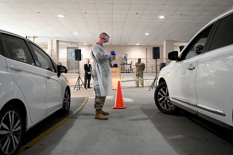 Thomas Cook, with the Arkansas Army National Guard, finishes administering a test for COVID-19 at a drive-thru screening site at UAMS on Tuesday, Jan. 4, 2022. Gov. Asa Hutchinson visited the medical campus to welcome 12 Arkansas National Guard soldiers who are helping with the demand at the drive-thru screening site. See more photos at arkansasonline.com/15uams/..(Arkansas Democrat-Gazette/Stephen Swofford)