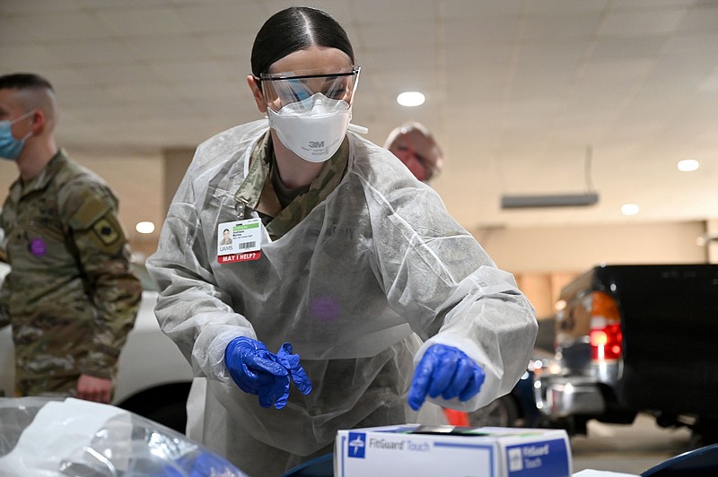 Audriana Morina, with the Arkansas Army National Guard, replaces her gloves between tests as she and 12 other soldiers help with demand at the drive-thru screening site at UAMS on Tuesday, Jan. 4, 2022. Gov. Asa Hutchinson visited the medical campus to welcome the 12 Arkansas National Guard soldiers, who arrived yesterday. See more photos at arkansasonline.com/15uams/..(Arkansas Democrat-Gazette/Stephen Swofford)