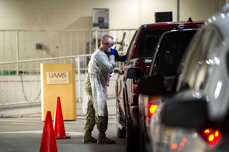 Thomas Cook, with the Arkansas Army National Guard, administers a test for COVID-19 at a drive-thru screening site at UAMS on Tuesday, Jan. 4, 2022. Gov. Asa Hutchinson visited the medical campus to welcome 12 Arkansas National Guard soldiers who are helping with the demand at the drive-thru screening site. See more photos at arkansasonline.com/15uams/..(Arkansas Democrat-Gazette/Stephen Swofford)