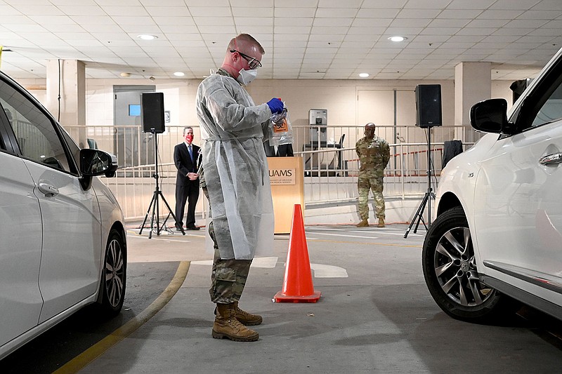 Thomas Cook, with the Arkansas Army National Guard, finishes administering a test for COVID-19 at a drive-thru screening site at UAMS on Tuesday, Jan. 4, 2022. Gov. Asa Hutchinson visited the medical campus to welcome 12 Arkansas National Guard soldiers who are helping with the demand at the drive-thru screening site. See more photos at arkansasonline.com/15uams/..(Arkansas Democrat-Gazette/Stephen Swofford)