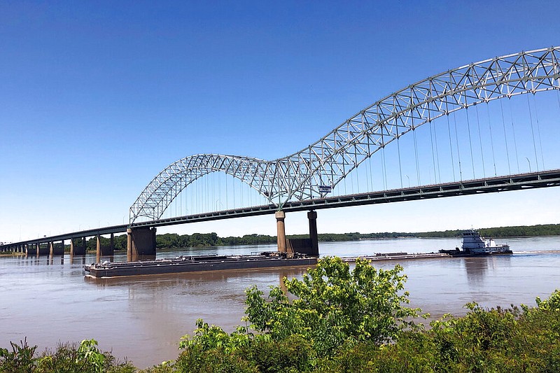 A tug boat, seen from the Memphis side of the Mississippi River, pushes barges down the river and under the Interstate 40 bridge linking Tennessee and Arkansas in this May 14, 2021, file photo. (AP/Adrian Sainz)