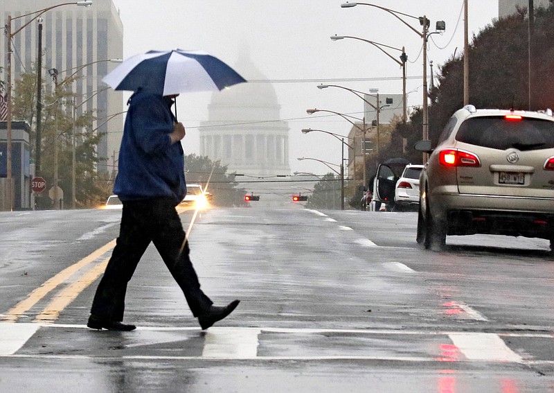 A pedestrian crosses West Capitol Avenue at Broadway in downtown Little Rock during a rain shower in this November 2018 file photo. The dome of the Capitol building is visible in the background. (Arkansas Democrat-Gazette file photo)