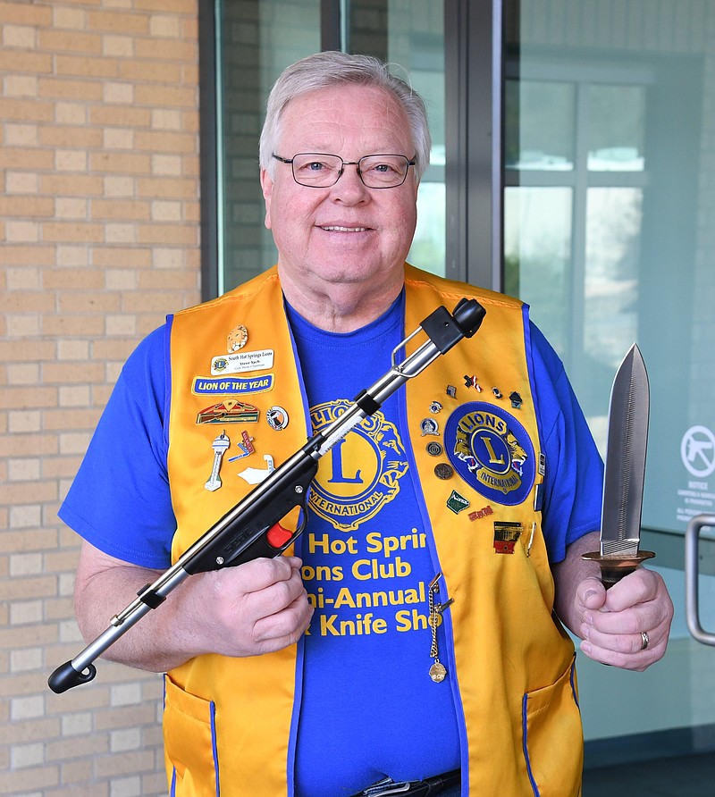 Steve Yach, South Hot Springs Lions Club Gun & Knife Show chairman, displays a spear gun and a dagger that will both be raffle items at the show this weekend at the Hot Springs Convention Center. - Photo by Tanner Newton of The Sentinel-Record