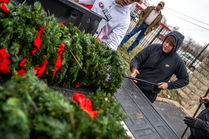 Avery Holland puts the last of the wreaths which were laid at the National Cemetery in the back of a truck Friday to be taken away. The wreaths were laid in December to honor veterans. (Ethan Weston/News Tribune)