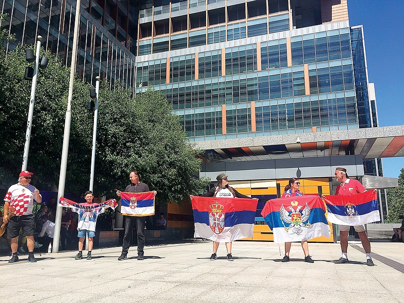 Supporters of Novak Djokovic hold their flags Sunday outside the Federal Court building in Melbourne, Australia. (Associated Press)