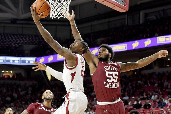 Arkansas guard Davonte Davis (4) drives past South Carolina forward Ta'Quan Woodley (55) to score during the first half of an NCAA college basketball game Tuesday, Jan. 18, 2022, in Fayetteville. (AP Photo/Michael Woods)
