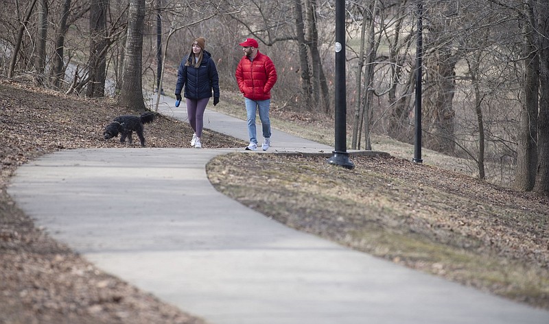 Elizabeth Parsley and Cole Brainerd, both of Fayetteville, walk their dog Sherman on a cold day in Wilson Park in Fayetteville in this Jan. 10, 2021, file photo. (NWA Democrat-Gazette/J.T. Wampler)