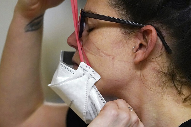 FILE - Registered nurse Jessalynn Dest pulls on a new N95 mask as indentations remain from another she had just removed after leaving a covid-19 patient room in the acute care unit of Harborview Medical Center, Jan. 14, 2022, in Seattle. (AP/Elaine Thompson, File)