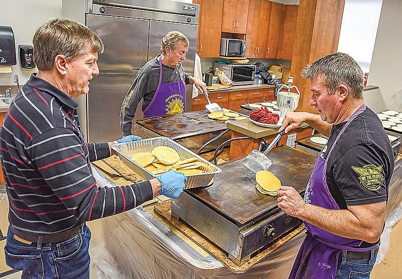 Steve Duncan, left, holds the tray while Eric Burkett, right, and Gary Anderson place the pancakes in. The Jefferson City Cosmopolitan Club hosted its 58th Pancake and Sausage Day at Selinger Center Wednesday, Jan. 19, 2022, the group's largest fundraiser of the year. (Julie Smith/News Tribune photo)