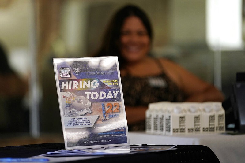 FILE - A hiring sign is placed at a booth for prospective employers during a job fair Wednesday, Sept. 22, 2021, in the West Hollywood section of Los Angeles. (AP/Marcio Jose Sanchez)