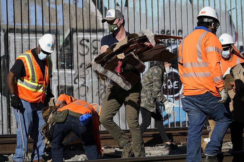 California Gov. Gavin Newsom removes cardboard from a Union Pacific railroad site Thursday in Los Angeles.
(AP/Ashley Landis)