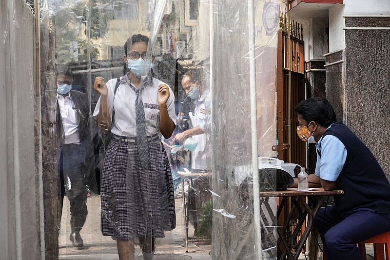 A student walks through a sanitization tunnel Friday on her way to receive a covid-19 shot at a private school in Kolkata, India.
(AP/Bikas Das)