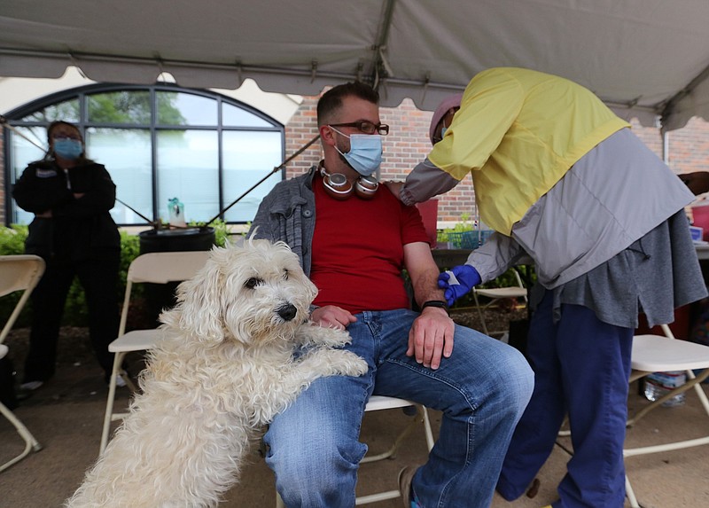 Michael Jevicky of Conway gets his second dose of the Pfizer covid-19 vaccine from nurse Cassandra Speer as his dog, Boudreaux, stands up on his lap during a vaccine clinic at the River Cities Travel Plaza in Little Rock on March 31, 2021. (Arkansas Democrat-Gazette/Thomas Metthe)