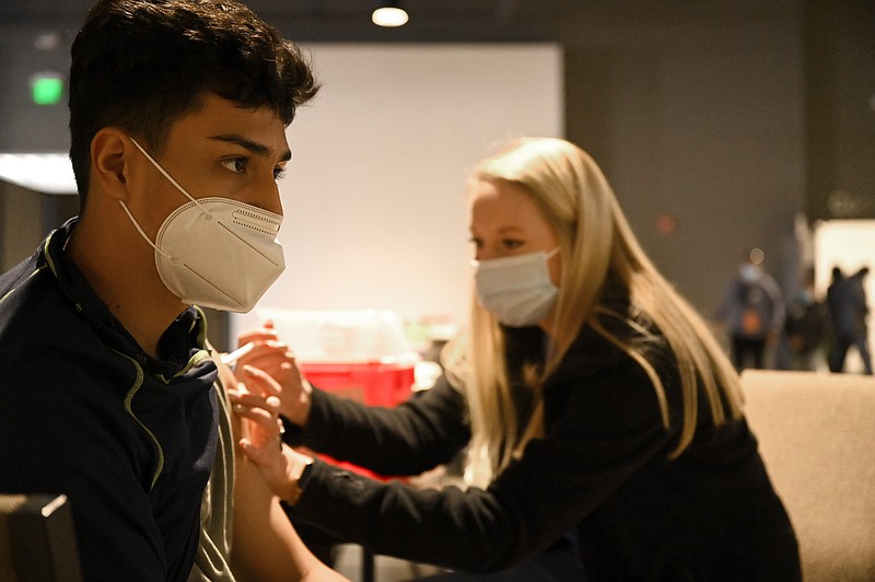Fredo De Los Santos, 16, left, receives a dose of the covid-19 vaccine from Lauren Romo, a pharmacy student, during a vaccine clinic at the Mosaic Church on Colonel Glenn Road in Little Rock on Saturday, Jan. 22, 2022. (Arkansas Democrat-Gazette/Stephen Swofford)
