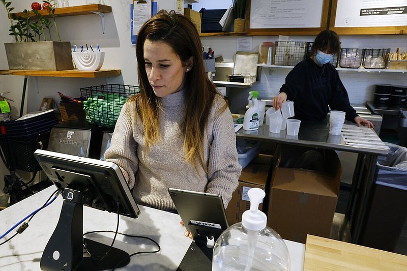 Deena Jalal, owner of plant-based ice cream chain FoMu, works behind the counter in her shop on Tremont Street in Boston on Friday, Jan. 14, 2022. Jalal says the cost of business overall rose 15% in 2021 compared to 2020. She has responded by raising prices about 10% and cutting back on some offerings. (AP/Michael Dwyer)