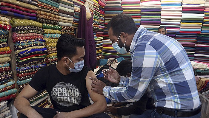 A health worker administers a Pakvac covid-19 shot to a shopkeeper Saturday at a market in Karachi, Pakistan. The country has seen a record increase in coronavirus cases in recent days.
(AP/Fareed Khan)