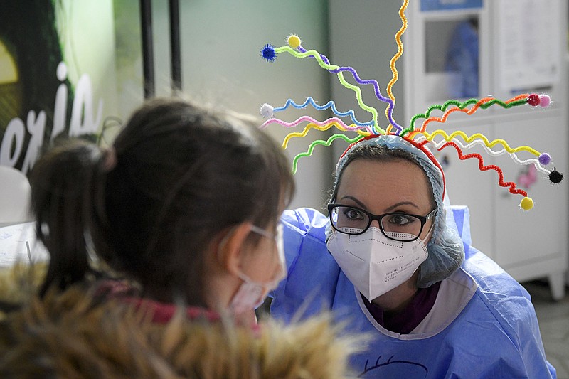 A medical worker talks to a child waiting to get her first Pfizer covid-19 shot Wednesday at a vaccination center in Bucharest, Romania. Romania has recorded a jump in coronavirus infections, hitting a pandemic record of nearly 35,000 daily cases, almost doubling its record set only a day earlier.
(AP/Andreea Alexandru)