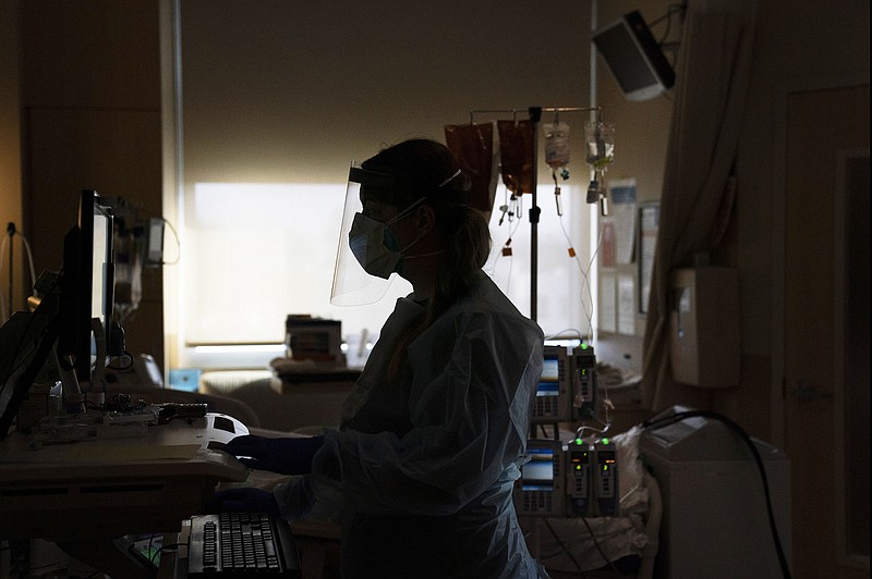 A registered nurse works on a computer while assisting a covid-19 patient in Los Angeles early in the pandemic. The surge in the omicron variant in the United States has made the strained staffing situation even more apparent in hospitals.
(AP/Jae C. Hong)