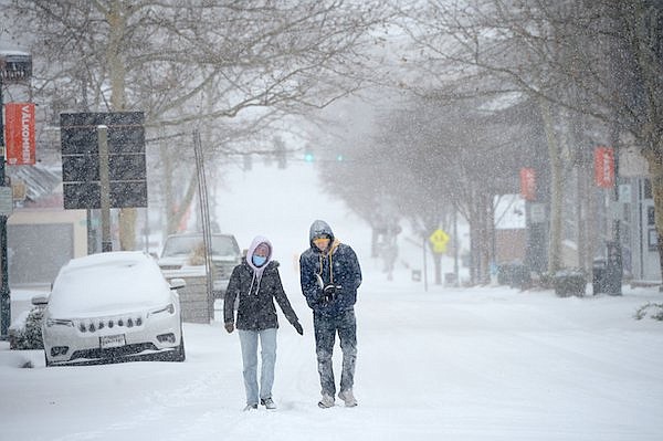 Quinn Maston (left) and Ben Hedrick, both University of Arkansas undergraduate students from McKinney, Texas, walk up Dickson Street Thursday, Feb. 3, 2022, as snow falls in Fayetteville.