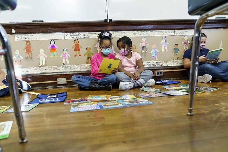 Second graders read together Wednesday at Raices Dual Language Academy, a public school in Central Falls, R.I. The state will lift its mask or proof-of-vaccination requirement for indoor businesses Friday, and plans on ending the statewide school mask mandate in early March.
(AP/David Goldman)