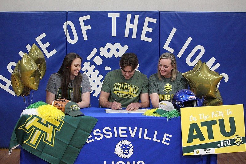 Jessieville quarterback Carson Hair signs to play at Arkanas Tech University surrounded by his sister, from left, Madison, and his mother Cassie Hair at Jessieville Sports Arena Wednesday. - Photo by Krishnan Collins of The Sentinel-Record