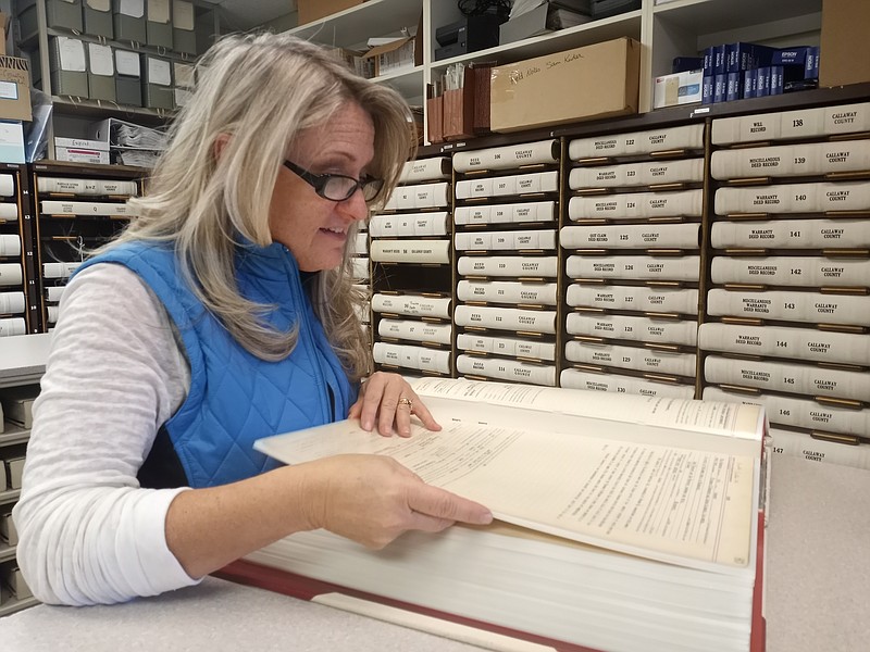 County Recorder of Deeds Christine Kleindienst flips through one of the more than 200 books of historical deeds kept in her office. (Michael Shine/Fulton Sun)