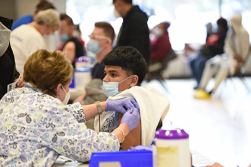 Retired nurse Margie Pullman gives Diego Juarez, 14, a dose of the Pfizer coronavirus vaccine Saturday at the Southwest Community Center in Little Rock. About 500 people got shots at the cityrun clinic, which offered $50 VISA gift cards as incentives. More photos at arkansasonline.com/213clinic/.
(Arkansas Democrat-Gazette/Staci Vandagriff)