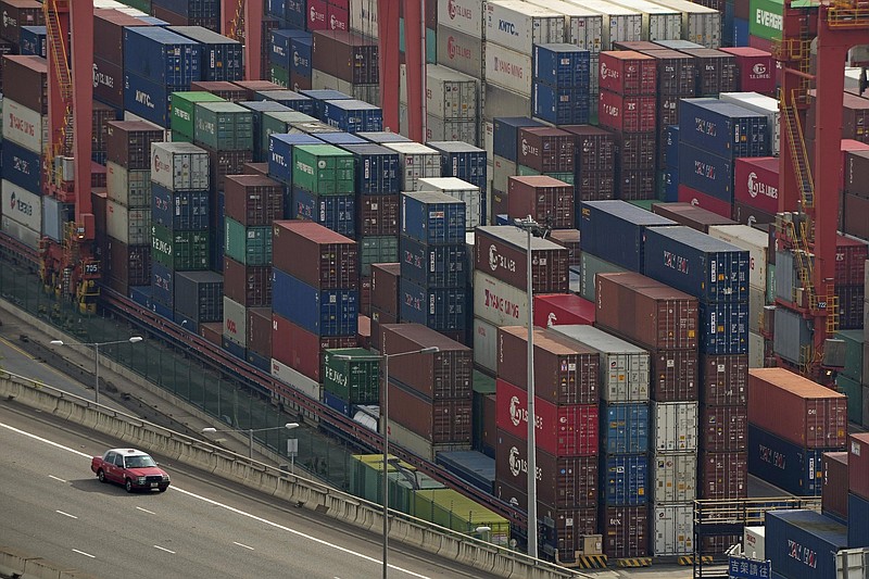 Shipping containers tower over a road at Kwai Tsing Container Terminals in Hong Kong in November. The United States accused China in a report Wednesday of flooding markets with cheap materials while also asking other countries to hand over prized technology in exchange for access to China’s markets.
(AP File)