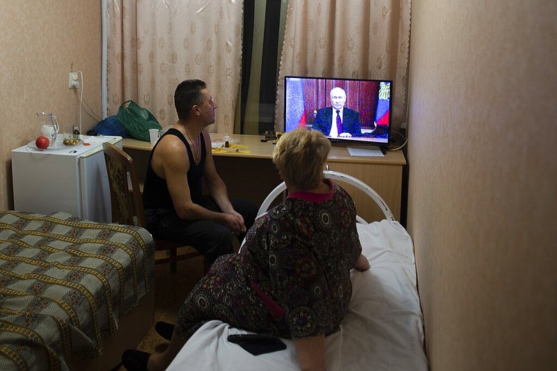 People from eastern Ukraine's Donetsk and Luhansk regions, the territory controlled by a pro-Russia separatist governments in eastern Ukraine, watch Russian President Vladimir Putin's address at their temporary place in Rostov-on-Don region, Russia, on Monday, Feb. 21, 2022. (AP/Denis Kaminev)