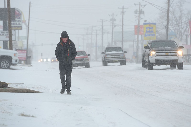 Dakota Brannan of Fort Smith walks through sleet Wednesday on Towson Avenue in Fort Smith. Nearly an inch of sleet accumulated throughout the day in the area, with more ice, freezing rain and other wintry precipitation expected today for much of the state.
(NWA Democrat-Gazette/Hank Layton)