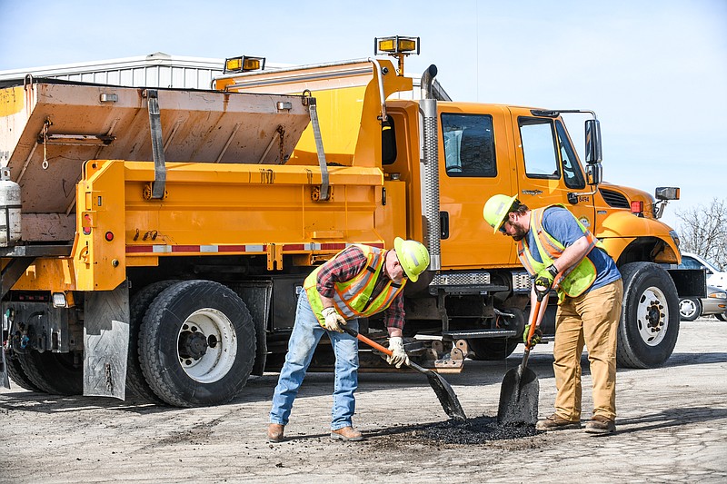 Vic Englage, left, and Grant Kleindienst, of MoDOT, pack hot asphalt into potholes on the entrance to MoDOT's Central Maintenance driveway in Jefferson City on Monday, Feb. 28, 2022. (Julie Smith/News Tribune photo)