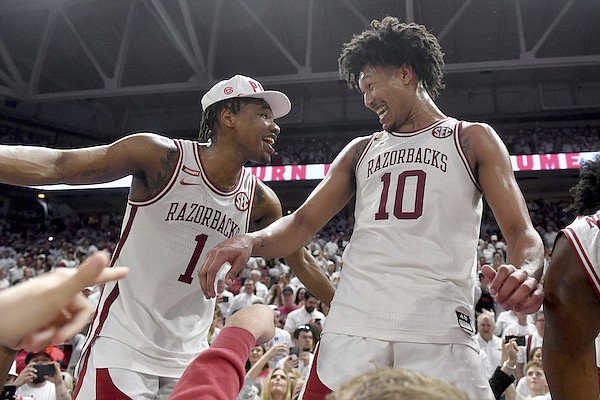 Arkansas players JD Notae (1) and Jaylin Williams (10) celebrate with fans after defeating Auburn 80-76 in overtime during an NCAA college basketball game Tuesday, Feb. 8, 2022, in Fayetteville, Ark. (AP Photo/Michael Woods)