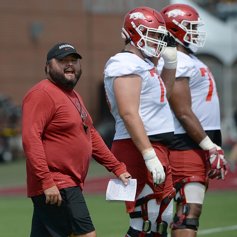 Arkansas assistant coach Cody Kennedy (left) speaks to the offensive line during practice last season. The Razorbacks lost only one starter on the line and is a position group filled with depth and competition heading into Sunday’s first spring practice. “I hope we have one of the better ones in the SEC,” Coach Sam Pittman said. “We’ve got experience.” (NWA Democrat-Gazette/Andy Shupe)