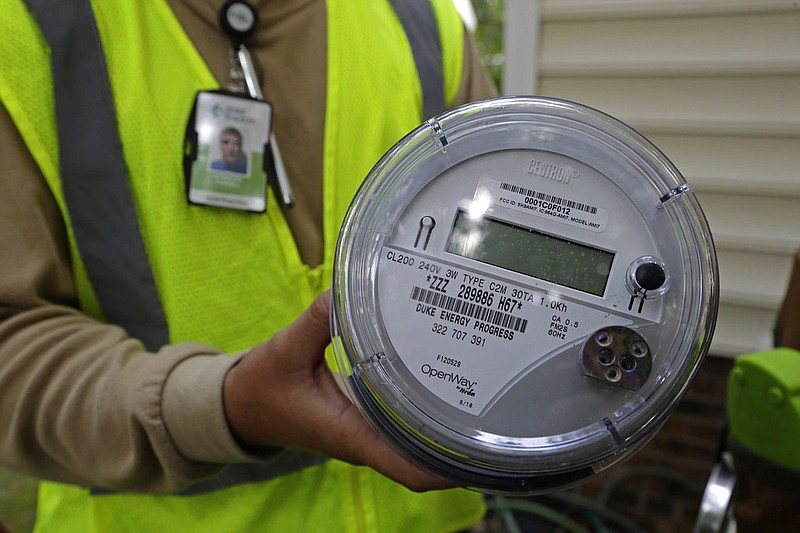 A worker holds a smart meter before its installation at a residence in this July 13, 2018, file photo. The meter replaces electric meters and transmits power-usage data wirelessly to an electric utility, ending the need for workers to visit a home and log power usage. (AP/Gerry Broome)