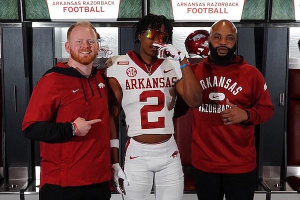Arkansas assistant defensive backs coach Mason Hutchins (left), safety recruit TJ Metcalf (center) and cornerbacks coach Dominque Bowman are shown during the Razorbacks' Prospect Day on Saturday, March 12, 2022, in Fayetteville.