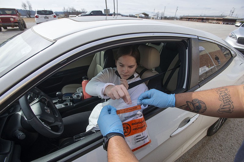 Lily Douglas of Fayetteville turns in a swab to get tested for the coronavirus that causes covid-19 at the Washington County Fairgrounds in Fayetteville in this Feb. 1, 2022, file photo. (NWA Democrat-Gazette/J.T. Wampler)