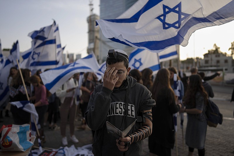 An Israeli youth prays next to right wing activists Wednesday as they protest against Israel’s Prime Minister Naftali Bennett, following a recent wave of violence, in Tel Aviv, Israel.
(AP/Oded Balilty)