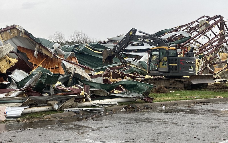 A trackho sifts through debris Wednesday, March 30, 2022 at George Elementary School in Springdale after a tornado swept through the city. (NWA Democrat-Gazette/FLIP PUTTHOFF)