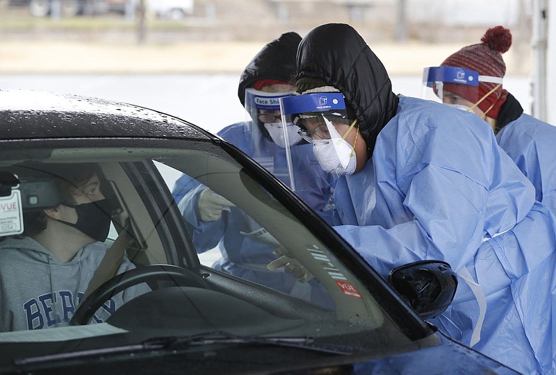 Medical personnel collect information from Trey Berry, a junior at the University of Arkansas, Fayetteville, in the parking lot across from Baum-Walker Stadium at the corner of Razorback Road and 15th Street in Fayetteville in this Jan. 6, 2021, file photo. Berry was about to get a covid-19 test during a drive-up coronavirus testing clinic hosted by the Arkansas Department of Health. (NWA Democrat-Gazette/David Gottschalk)
