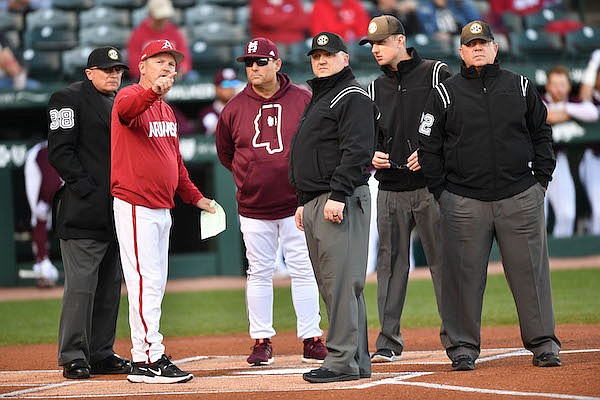 Arkansas coach Dave Van Horn (front) talks with umpires and Mississippi State coach Chris Lemonis prior to a game Friday, April 1, 2022, in Fayetteville.