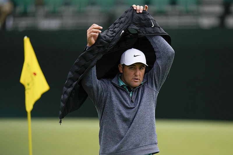 Scottie Scheffler puts on a vest on the fifth hole Saturday. With a wind chill in the upper 40s most of the day, Scheffler overcame the elements to maintain his lead going into today’s final round.
(AP/Jae C. Hong)