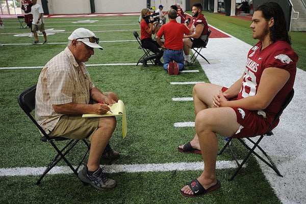 Arkansas offensive lineman Dalton Wagner (right) is interviewed Saturday, Aug. 3, 2019, by Clay Henry of Hawgs Illustrated during Media Day inside the Willard and Pat Walker Pavilion on the university campus in Fayetteville.