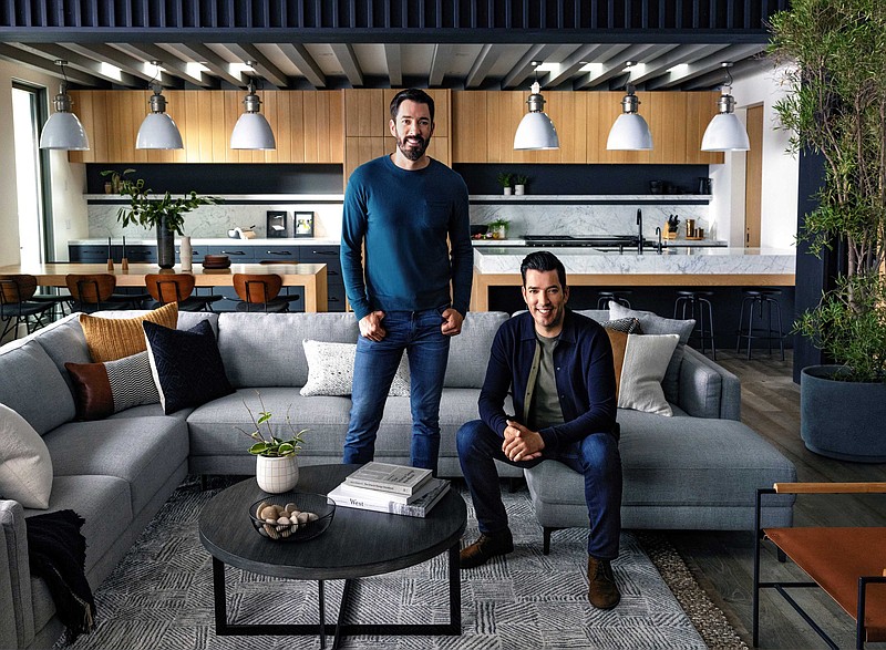 “Property Brothers” hosts Drew Scott, standing, and his brother, Jonathan Scott, look right at home in a room furnished with pieces from their new furniture line. The Drew & Jonathan for Living Spaces collection debuted April 11 and is available in all 20 Living Spaces stores and online with free shipping nationwide. (Courtesy of LivingSpaces.com.)
