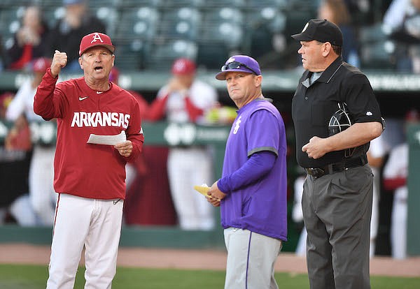Arkansas coach Dave Van Horn (left), LSU coach Jay Johnson (center) and umpire Mark Winters are shown prior to a game Thursday, April 14, 2022, in Fayetteville.